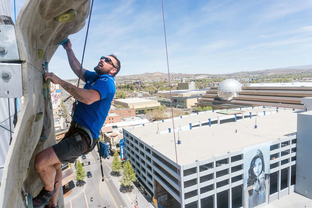 Ambassador Rock Climbing with part of the Reno skyline under him.