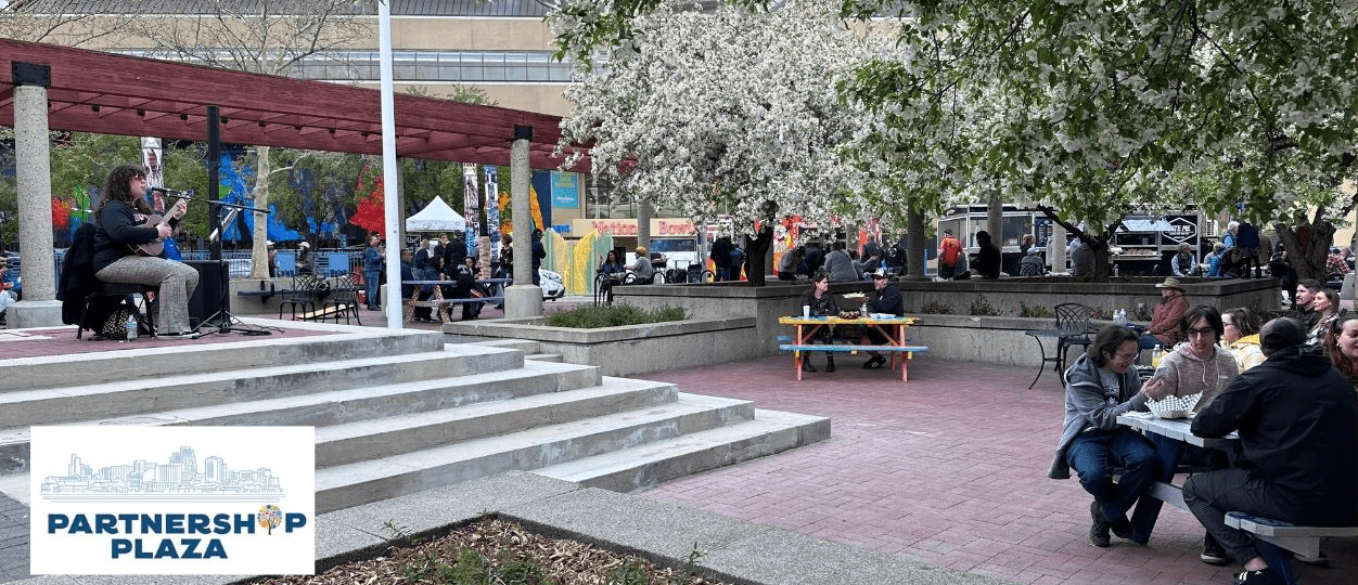 Downtown Tuesdays with a musician playing live music and people sitting in picnic tables around.