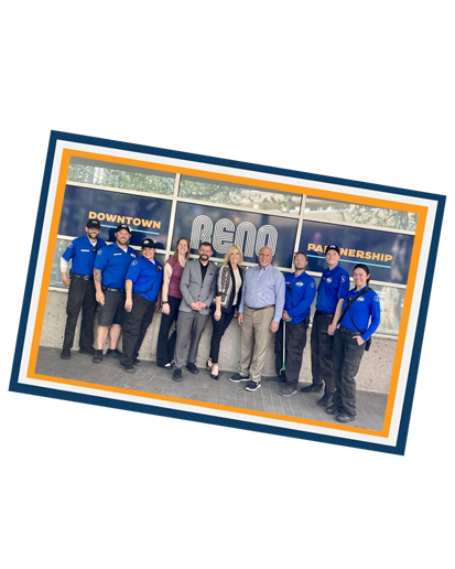 DRP Team with ambassadors standing in front of the Downtown Reno Partnership offices in a gold, blue, and white frame.