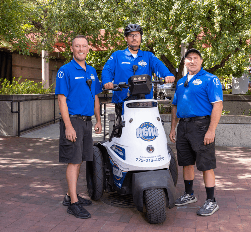 Three ambassadors posing together in the Partnership Plaza, with one ambassaor in the middle on a segway.