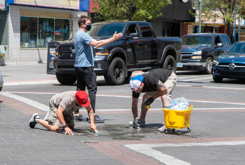 Downtown Reno Partnership Operations Manager Grant Denton and Cary DeMars scrubbing the crosswalk to get rid of graffiti during a May 31, 2020 clean up of downtown after a riot the previous night. Downtown Reno Partnership Executive Director Alex Stettinski directed traffic so they could finish the work safely.